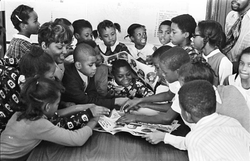 Black children gathered around book